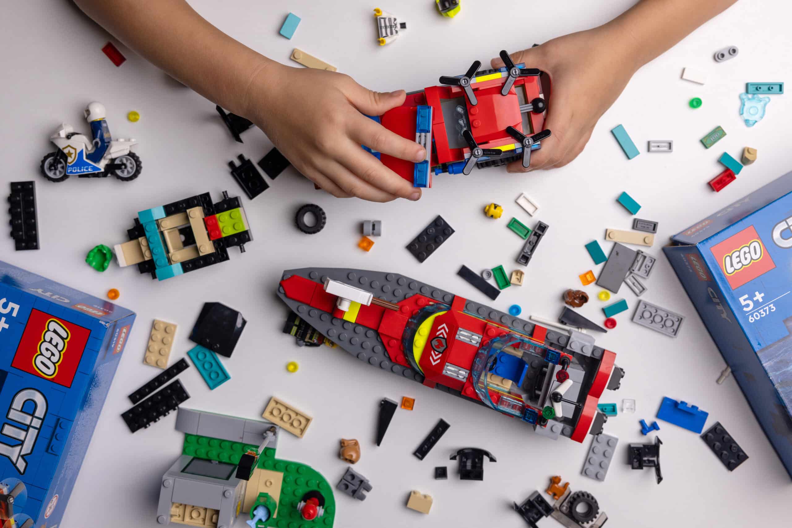 child playing with lego constructor on the table. building a firefighter car.