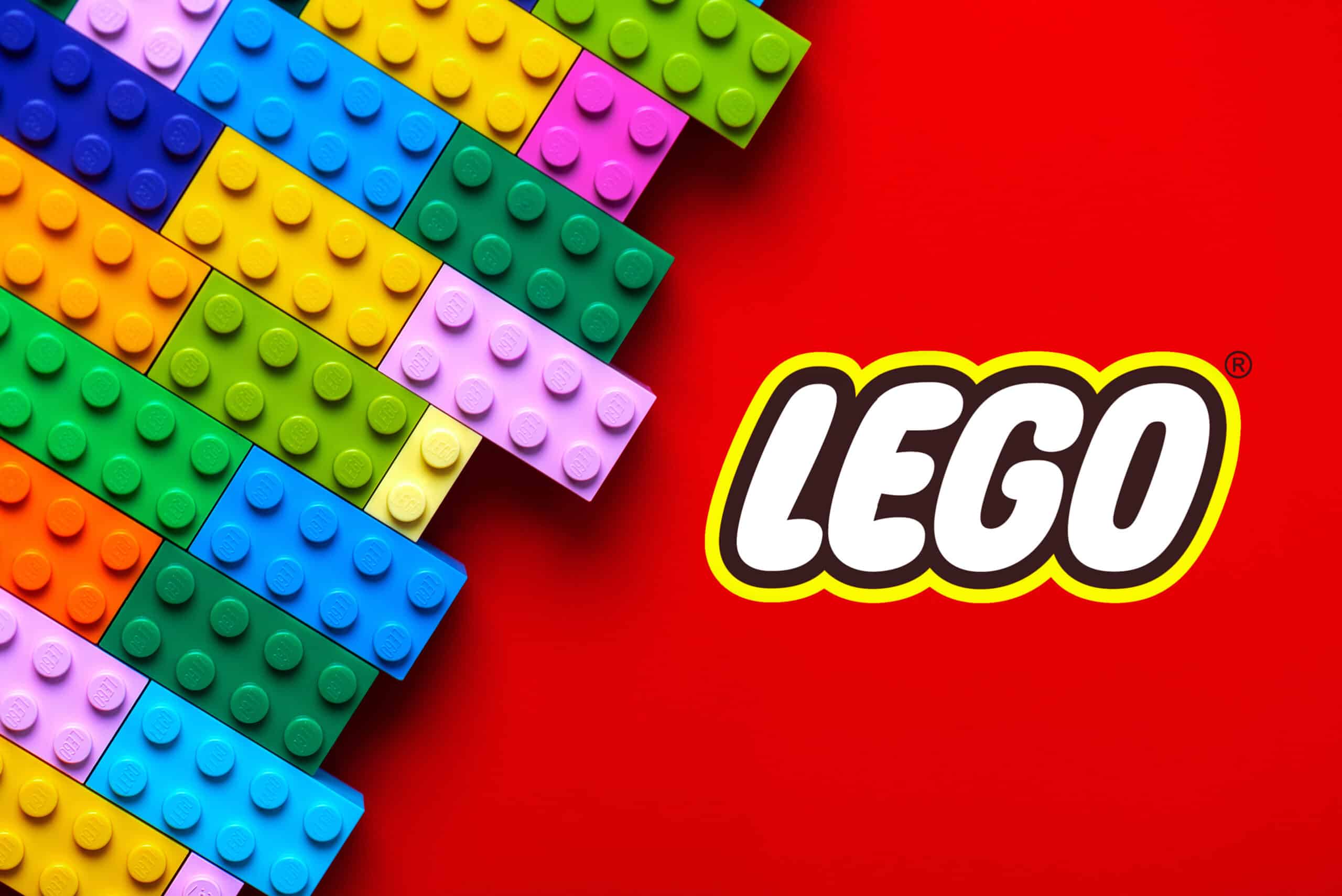 Close up of colorful Lego blocks with the Lego logo over red background.